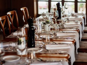 A long dining table set with multiple wine glasses, plates, and cutlery, indicating a formal dining arrangement.