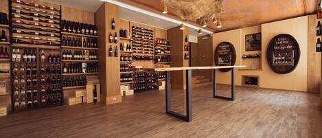 Una bodega con estantes de madera y una mesa central, que presenta una variedad de botellas de vino y un colgador de luces.