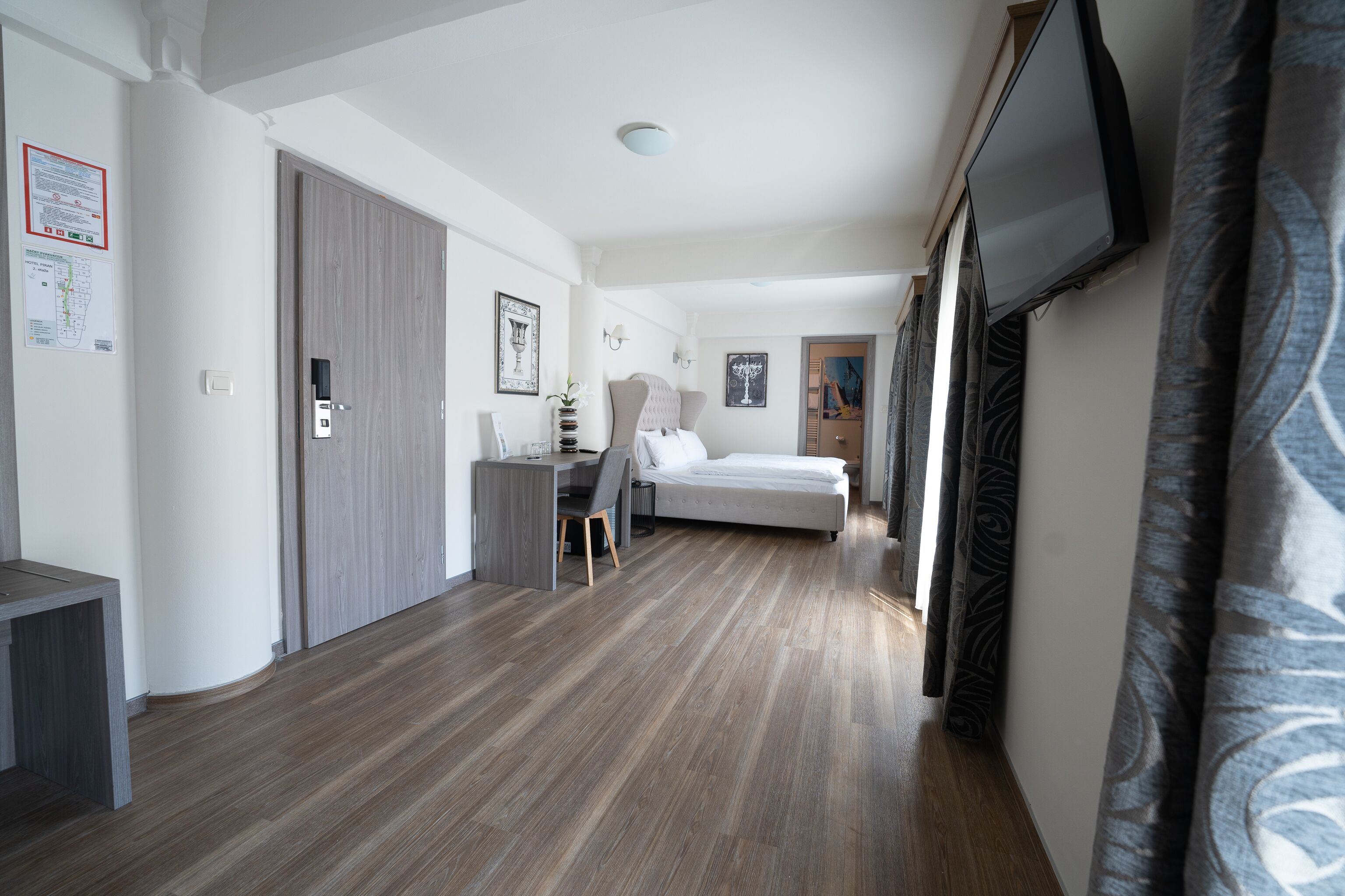 A hotel room with a bed, desk, chair, and a TV mounted on the wall.