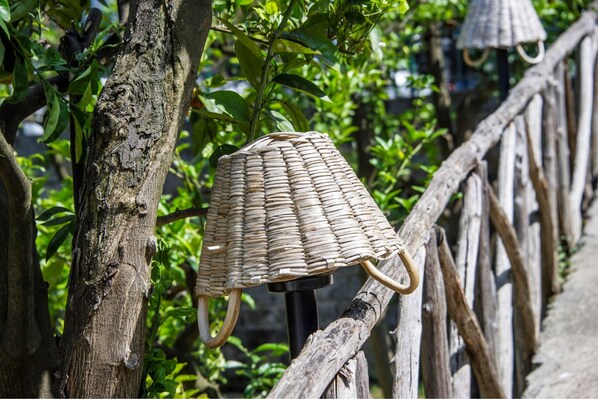 A wicker chair with a curved backrest and two handles, attached to a wooden post.