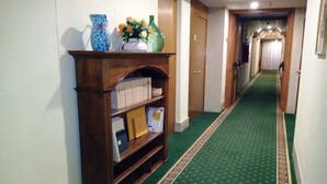 A hallway with a green carpet and a wooden bookshelf. - Hotel Select (Montecchio Emilia)