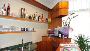 A kitchen with a wooden countertop, a sink, and shelves with bottles and glasses. - Hotel Select (Montecchio Emilia)
