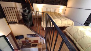 Une chambre avec un lit, une petite kitchenette et un escalier.