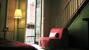 Une pièce comprenant un lit, une chaise, une lampe et une fenêtre donnant sur l’extérieur.