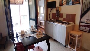 Une cuisine compacte avec un coin repas, un petit tabouret et un téléviseur fixé au mur.