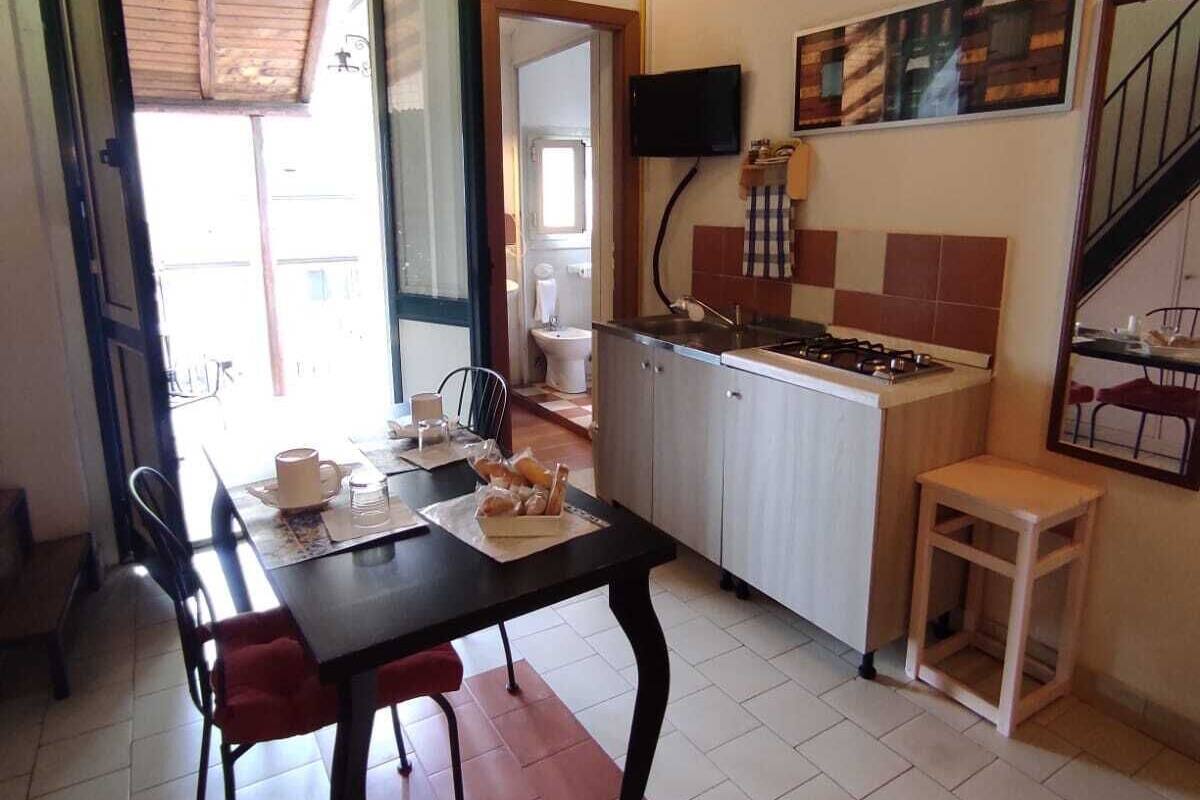 Une cuisine compacte avec un coin repas, un petit tabouret et un téléviseur fixé au mur.