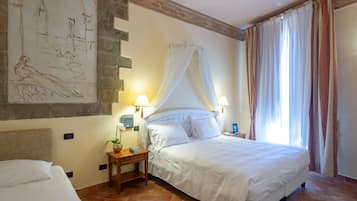 Quarto de hotel com uma cama grande, mesa de cabeceira com luminária, relógio fixado na parede e janela com cortinas.