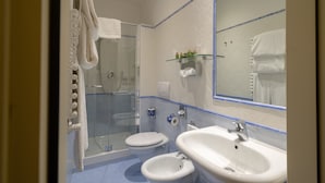 A bathroom with a glass shower enclosure, two toilets, a sink, and a mirror. - Davanzati (Florence)