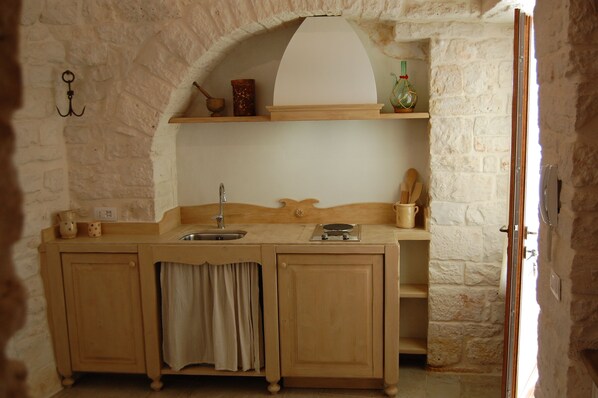 Una cocina rústica con mostrador de madera, un lavamanos y un colgador para ollas.