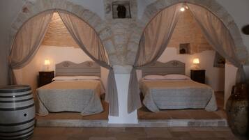 Two beds with canopy beds, stone walls, and a rustic ambiance.