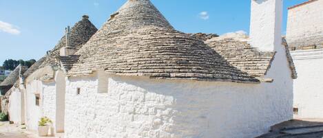 A traditional white stone building with a conical roof and a chimney.