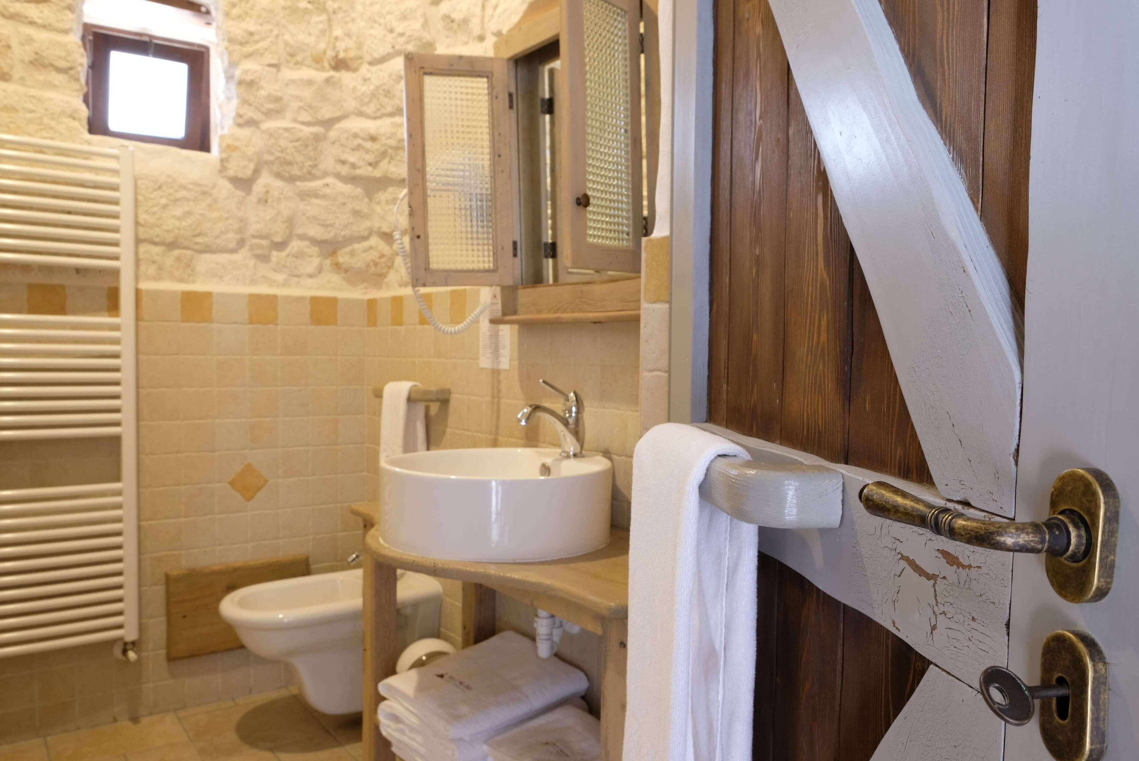 Un bagno con un lavandino bianco, un water, un portasciugamani e uno spazio doccia.