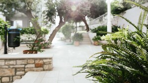 A pathway lined with potted plants and a stone wall, leading to a white building with a staircase. - Aparthotel Pharia (Hvar)