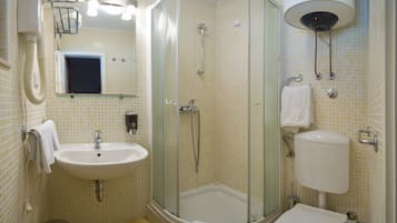 A bathroom with a sink, toilet, shower, and a glass-enclosed shower stall.