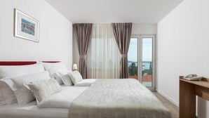 A hotel room with a bed, a desk, and a view of the sea. - Aparthotel Pharia (Hvar)