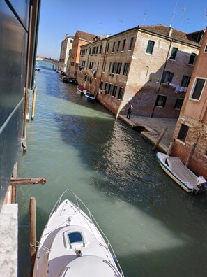 A narrow canal with boats docked on the right, surrounded by historic buildings with visible balconies and windows. - Alloggi Acquavita (Venice)