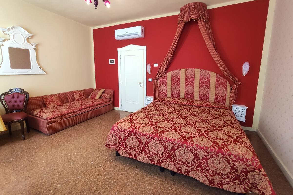 A bedroom with a large bed, a sofa, a chair, and a ceiling light fixture.