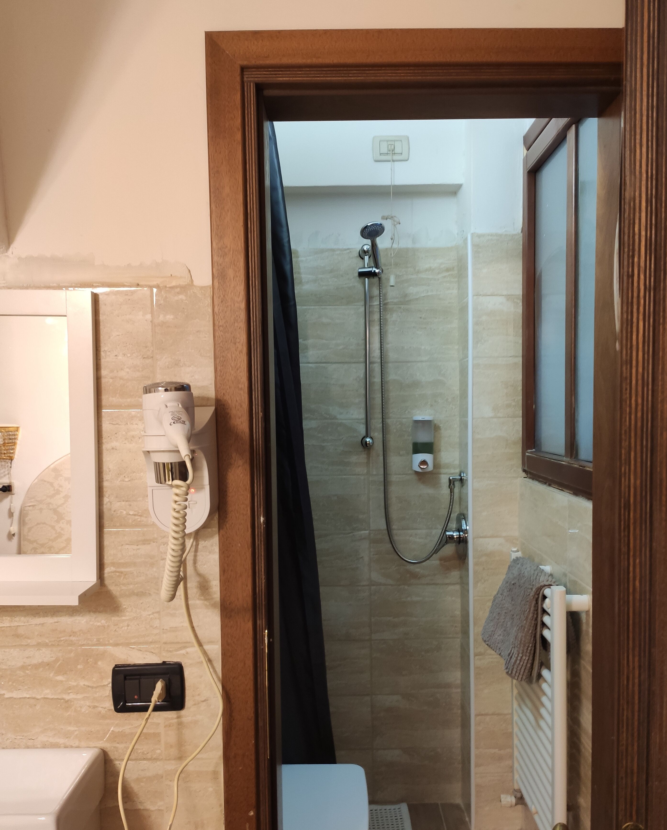 A bathroom with a shower, a hairdryer, and a towel rack.
