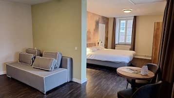 Een hotelkamer met een bank, een bed, een eettafeltje en een stoel.