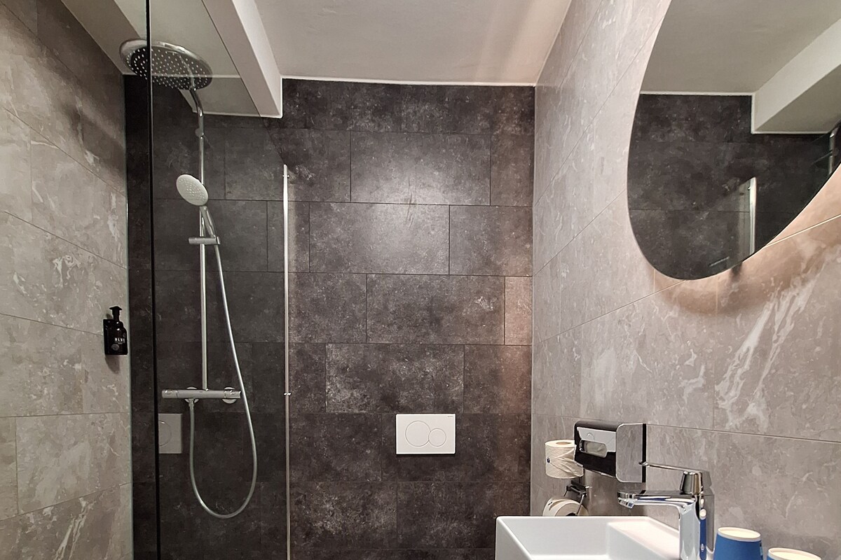 Une salle de bain moderne avec une douche à parois de verre, des toilettes blanches et un meuble-lavabo doté d’un évier et d’un porte-serviettes.