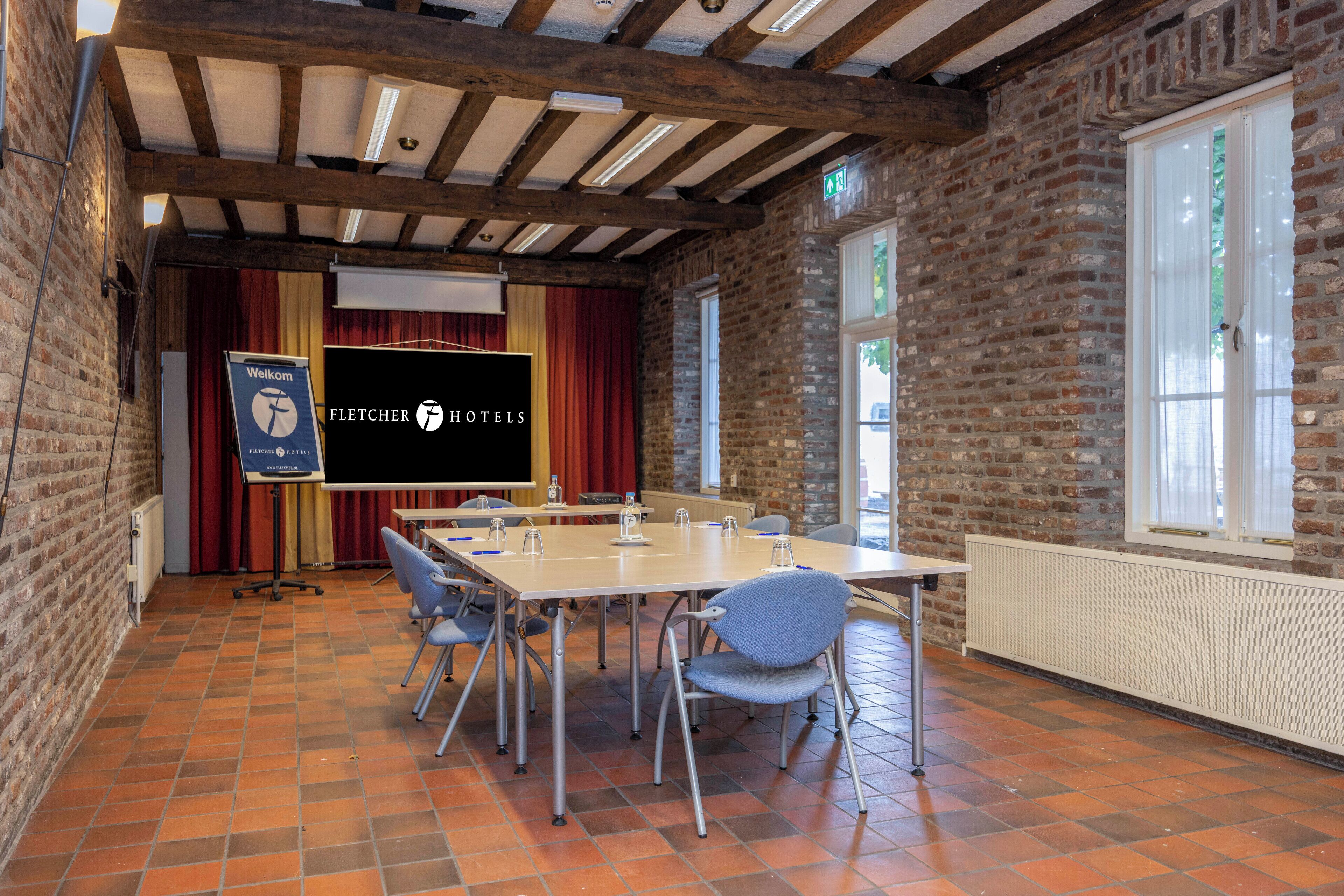 Ein Konferenzraum mit einem langen Tisch, Stühlen, einer Projektionsleinwand und einem 'Welcome'-Schild.