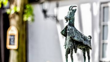 Een bronzen beeld van een geit op een voetstuk.