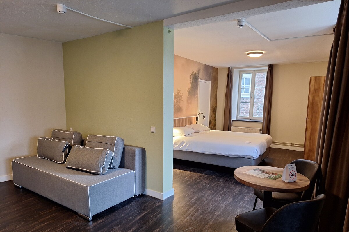 Une chambre d’hôtel avec un canapé, un lit, une table ronde et une chaise.