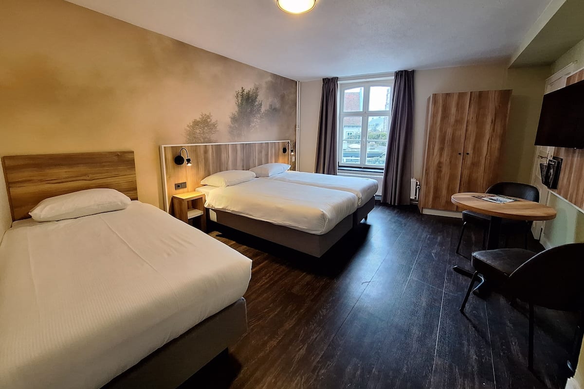 Een hotelkamer met twee bedden, een bureau en een stoel.