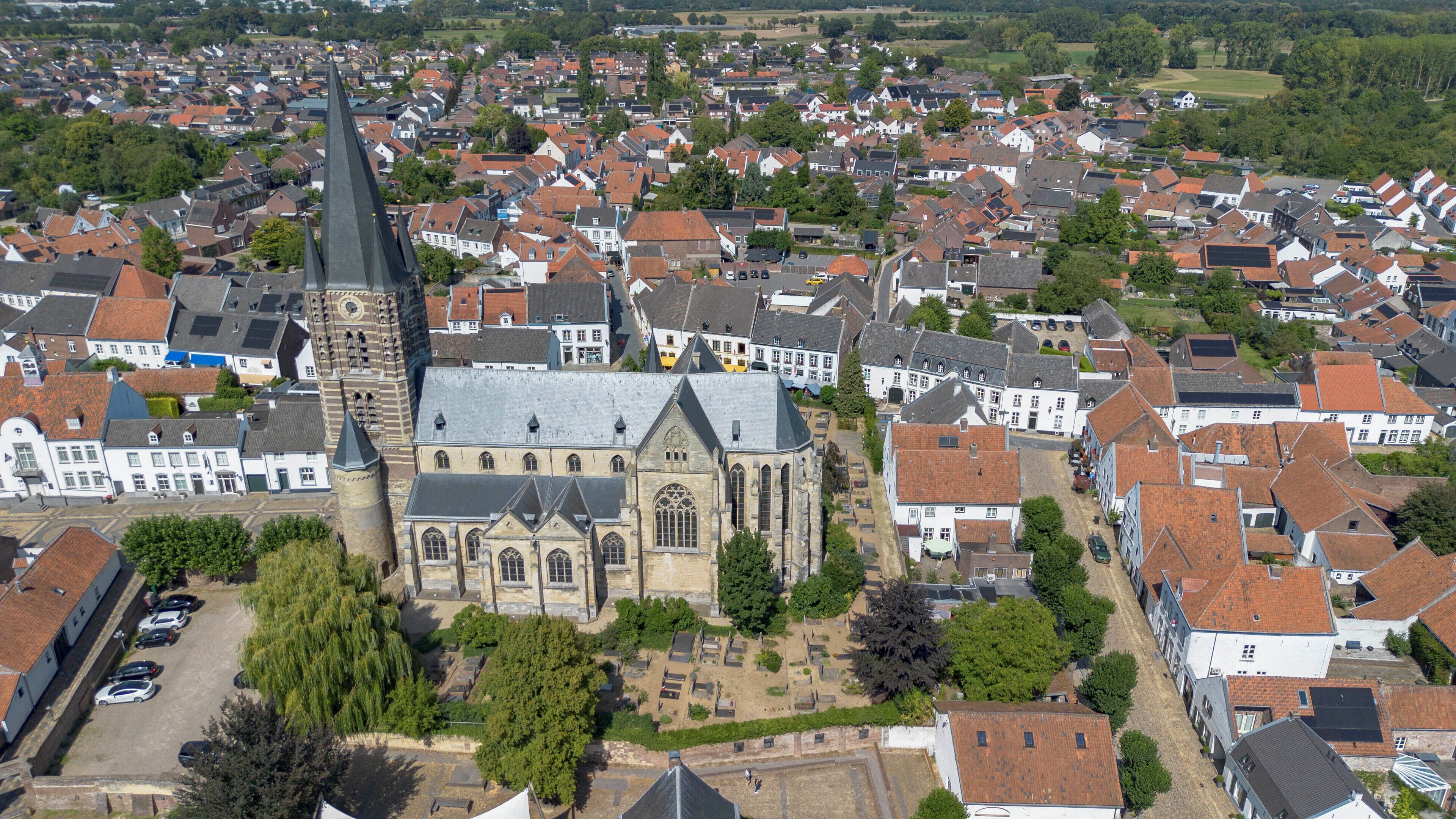 An aerial view of a town with a prominent church featuring a tall spire and a large courtyard.