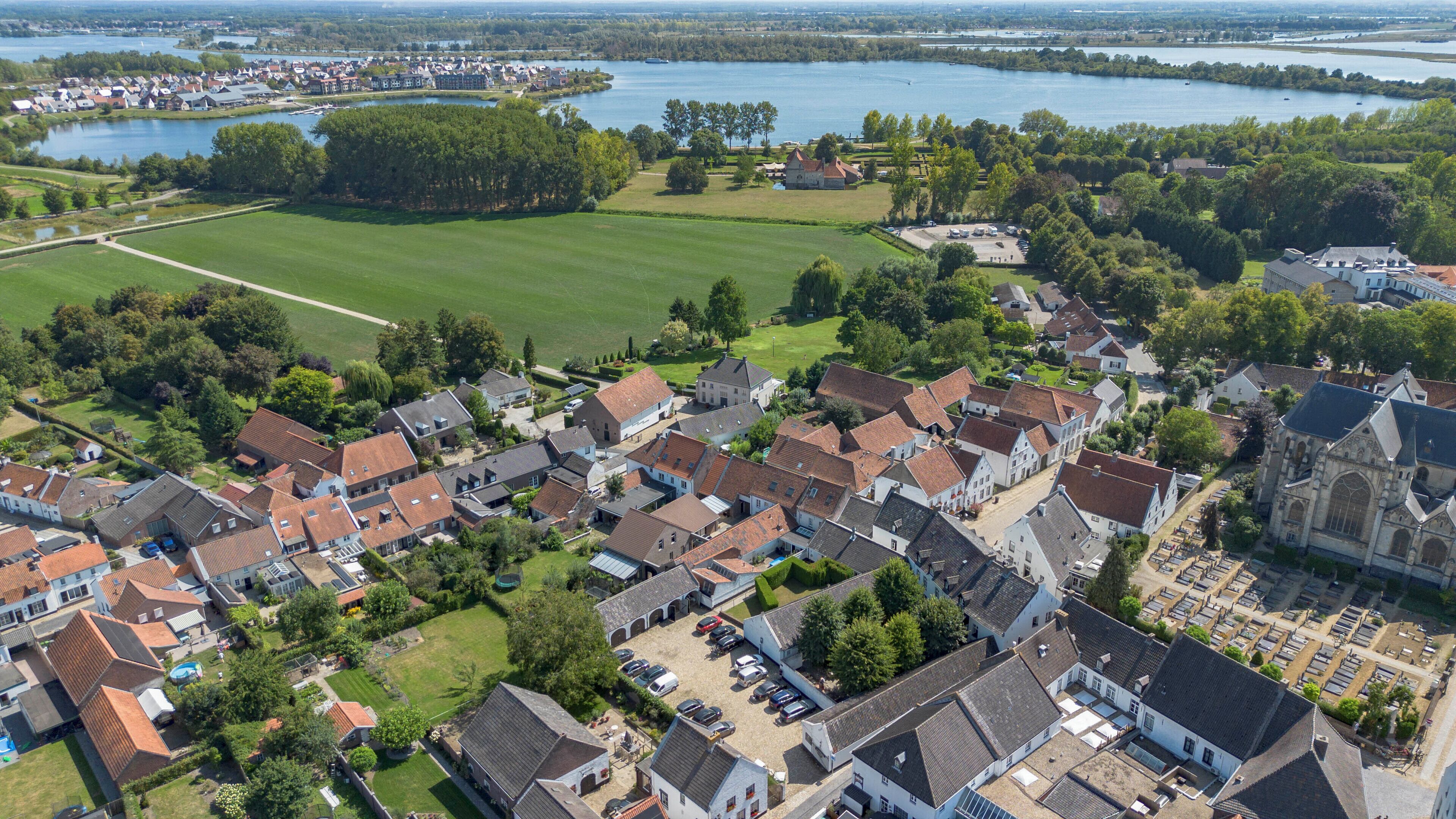 Vista aérea de una zona residencial con casas, una iglesia y un campo abierto extenso.