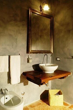A bathroom with a wooden vanity, a white sink, a mirror, and a towel rack. - Podere Monti (Montepulciano)