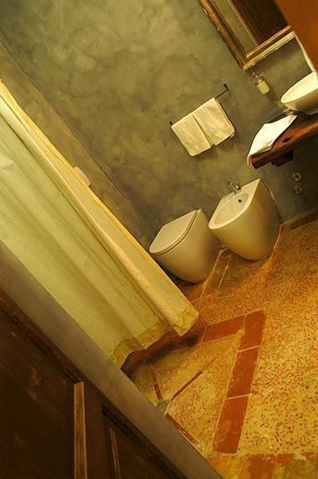 Ein Badezimmer mit Dusche, zwei Toiletten und einem Waschbecken.