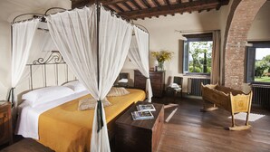 A bedroom with a four-poster bed, wooden flooring, a small wooden chest, and a view of the outdoors through a window. - Podere Monti (Montepulciano)