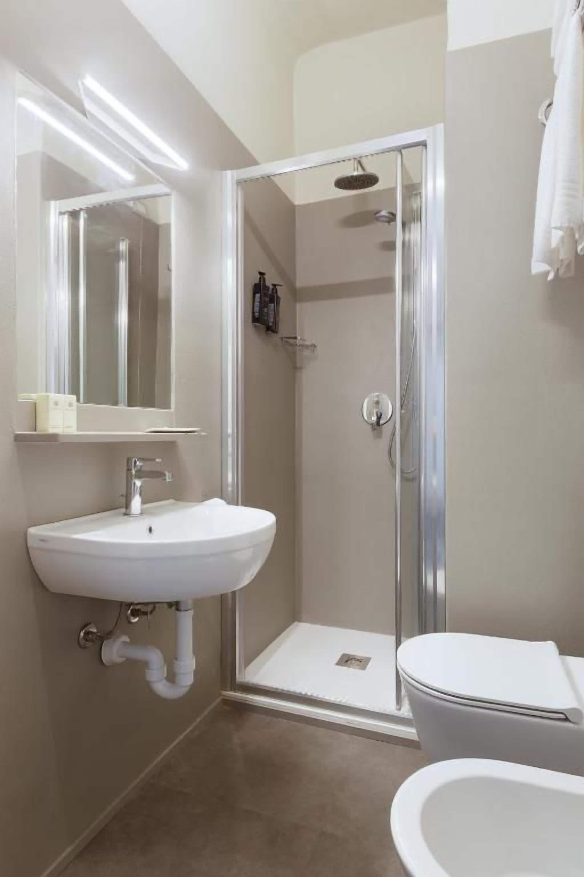 Une salle de bain avec douche, toilettes et lavabo.