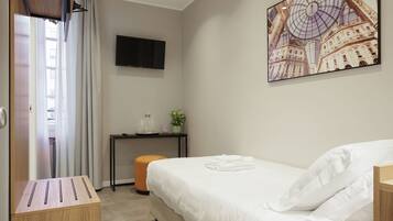 Habitación de hotel con cama, escritorio, televisión y un cuadro en la pared.