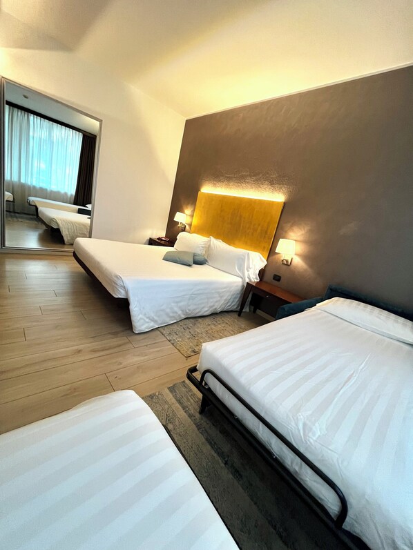 Ein Hotelzimmer mit zwei Betten, einem großen Spiegel und Holzboden.