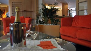 En moderne stue med et glasbord, røde sofaer, en champagneflaske og et glas vin.