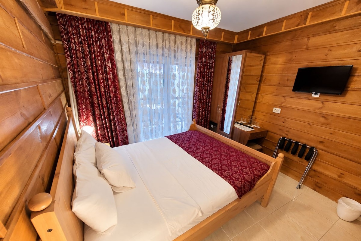 Une pièce en bois avec un lit, une télévision et une fenêtre avec des rideaux.
