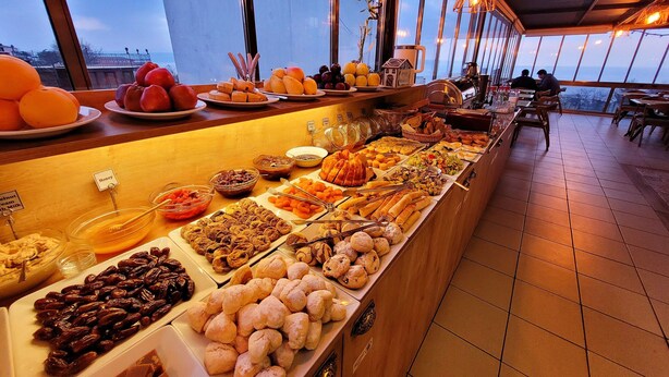 Een buffet met diverse gerechten en een uitzicht op de stad door grote ramen.