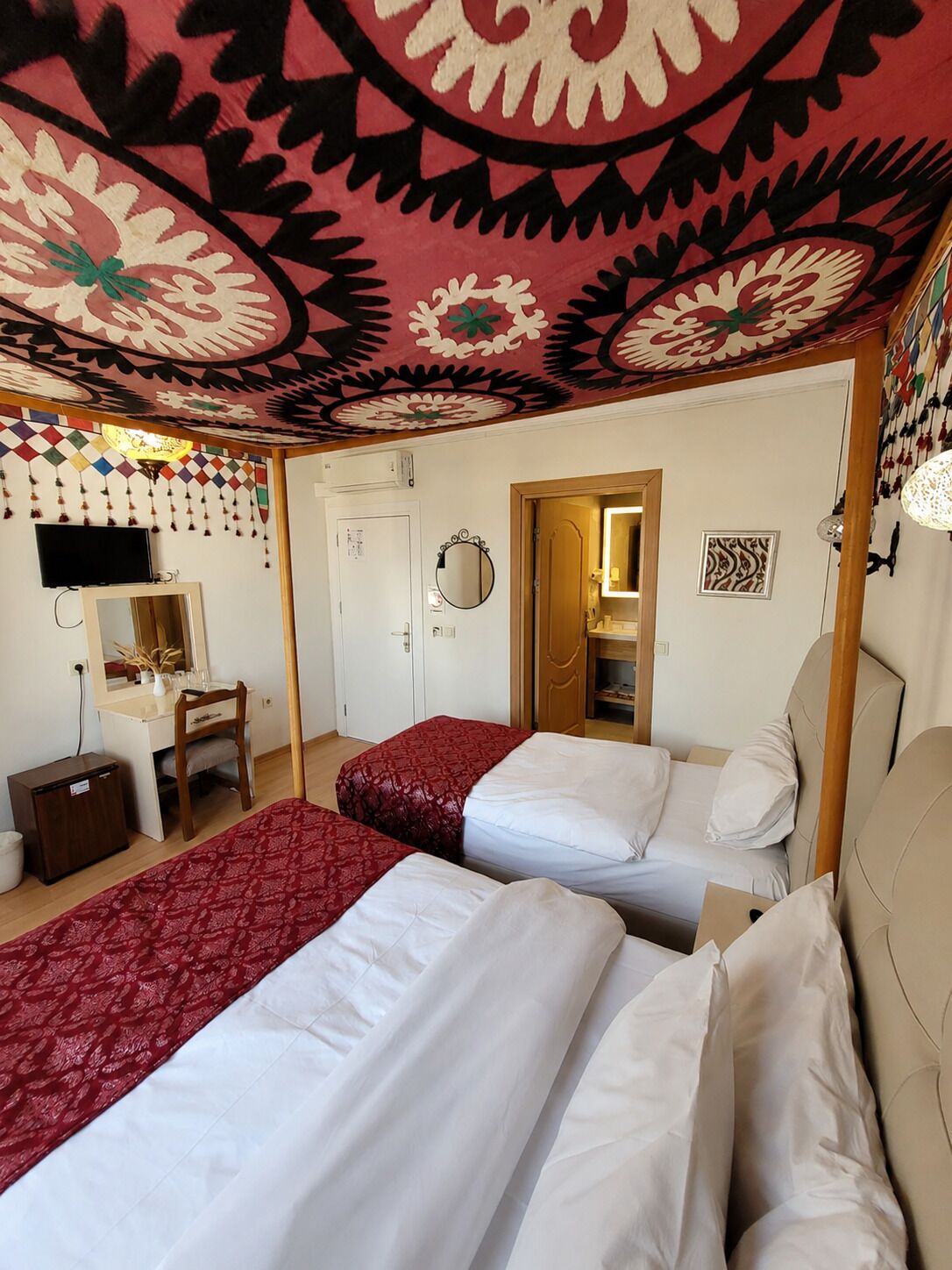 Een hotelkamer met twee bedden, een bureau, een stoel, een televisie en een spiegel.