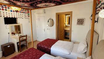 Een hotelkamer met twee bedden, een bureau, een stoel, een televisie en een spiegel.