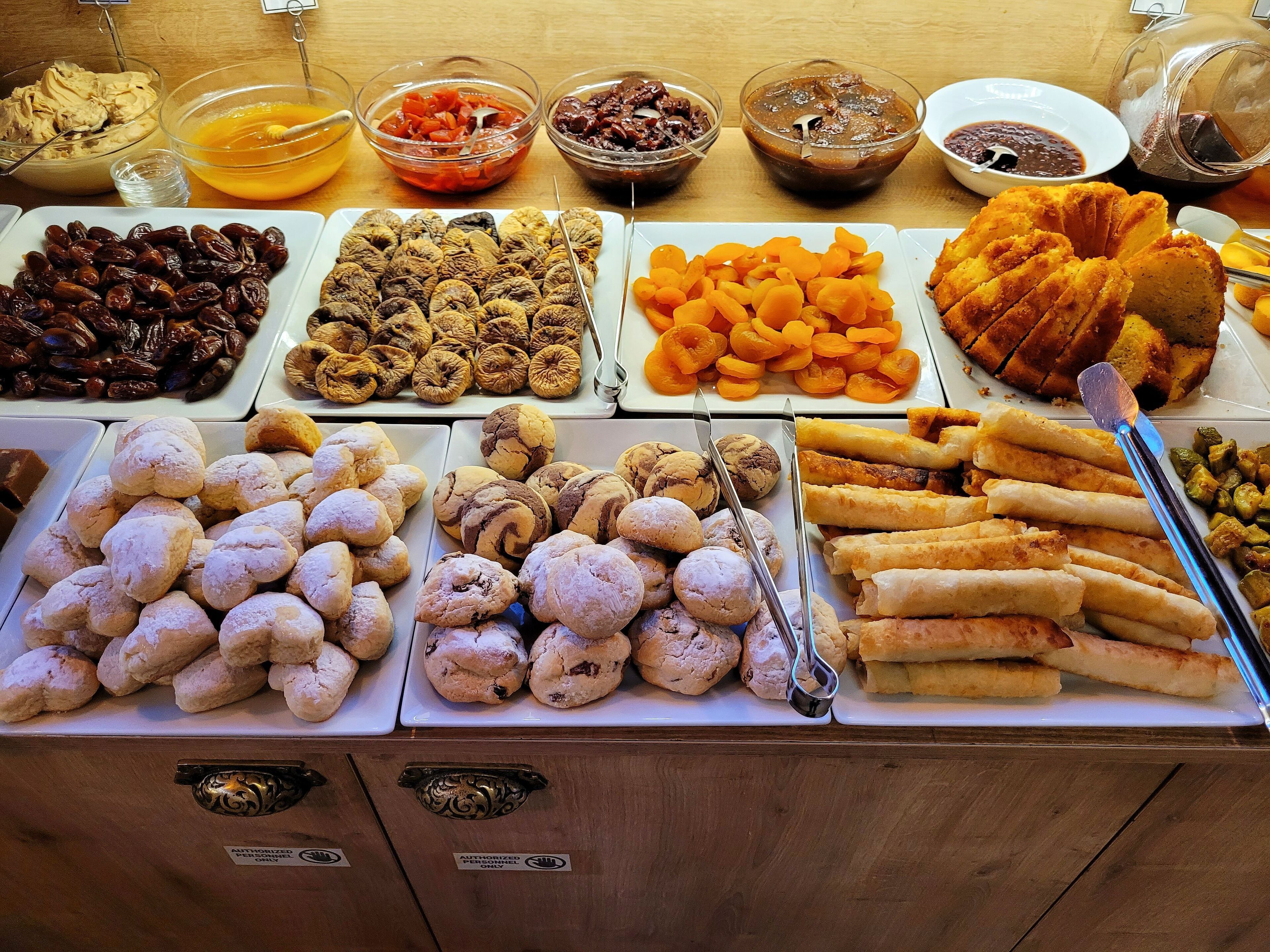 A buffet table with various food items including pastries, fruits, and condiments.