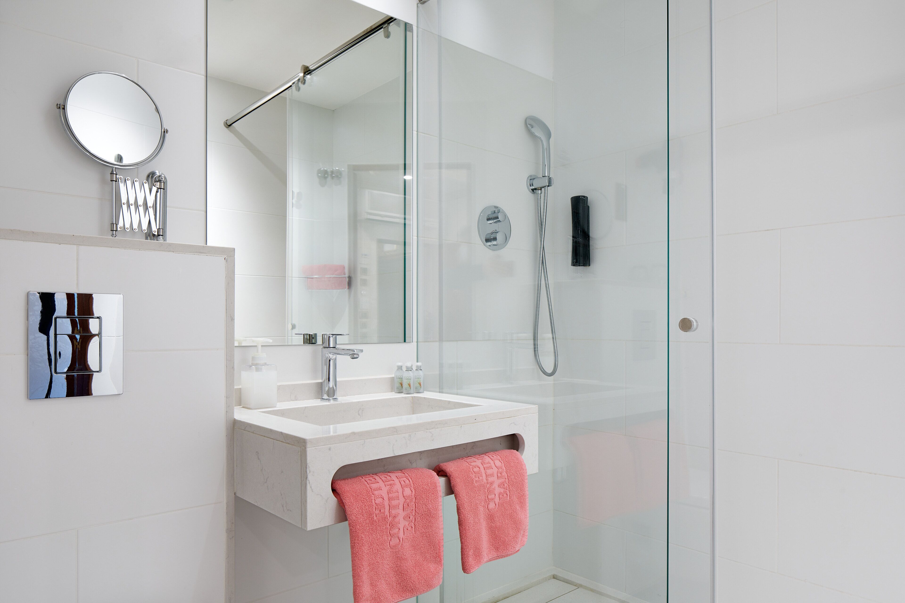 Un baño moderno con ducha envuelta en vidrio, un lavabo blanco y un espejo grande.