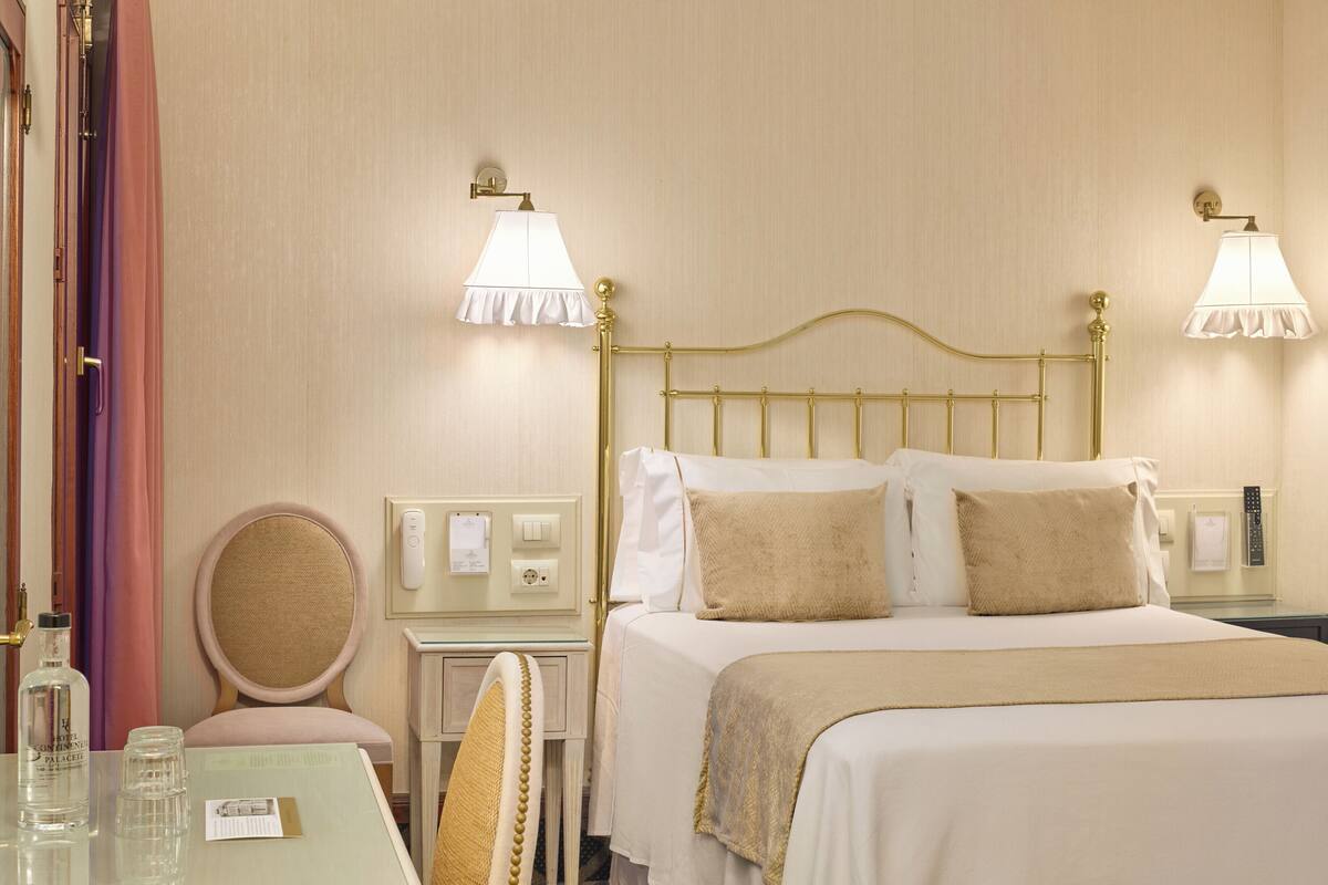 Une chambre d’hôtel comprenant un lit, des tables de chevet, une chaise et des lampes.