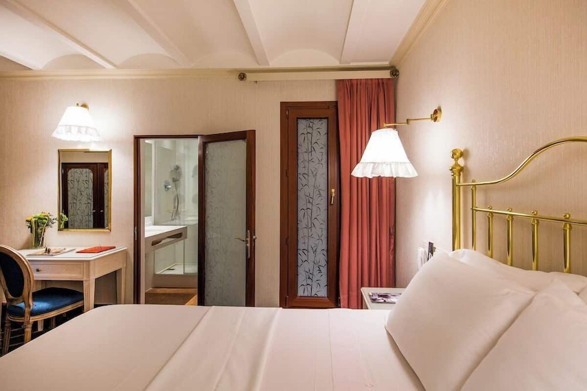 Une chambre d’hôtel avec un lit, un bureau, une chaise et un miroir.