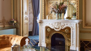 Una habitación opulenta con un espejo imponente, una chimenea y un candelabro.