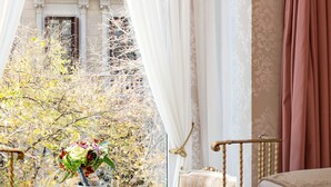 Una habitación con una mesa dispuesta para dos personas, una silla, una cama y vistas a un edificio con balcones.