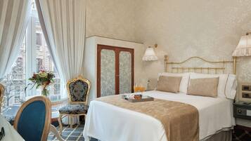 A hotel room with a bed, a chair, a table, and a window with curtains.