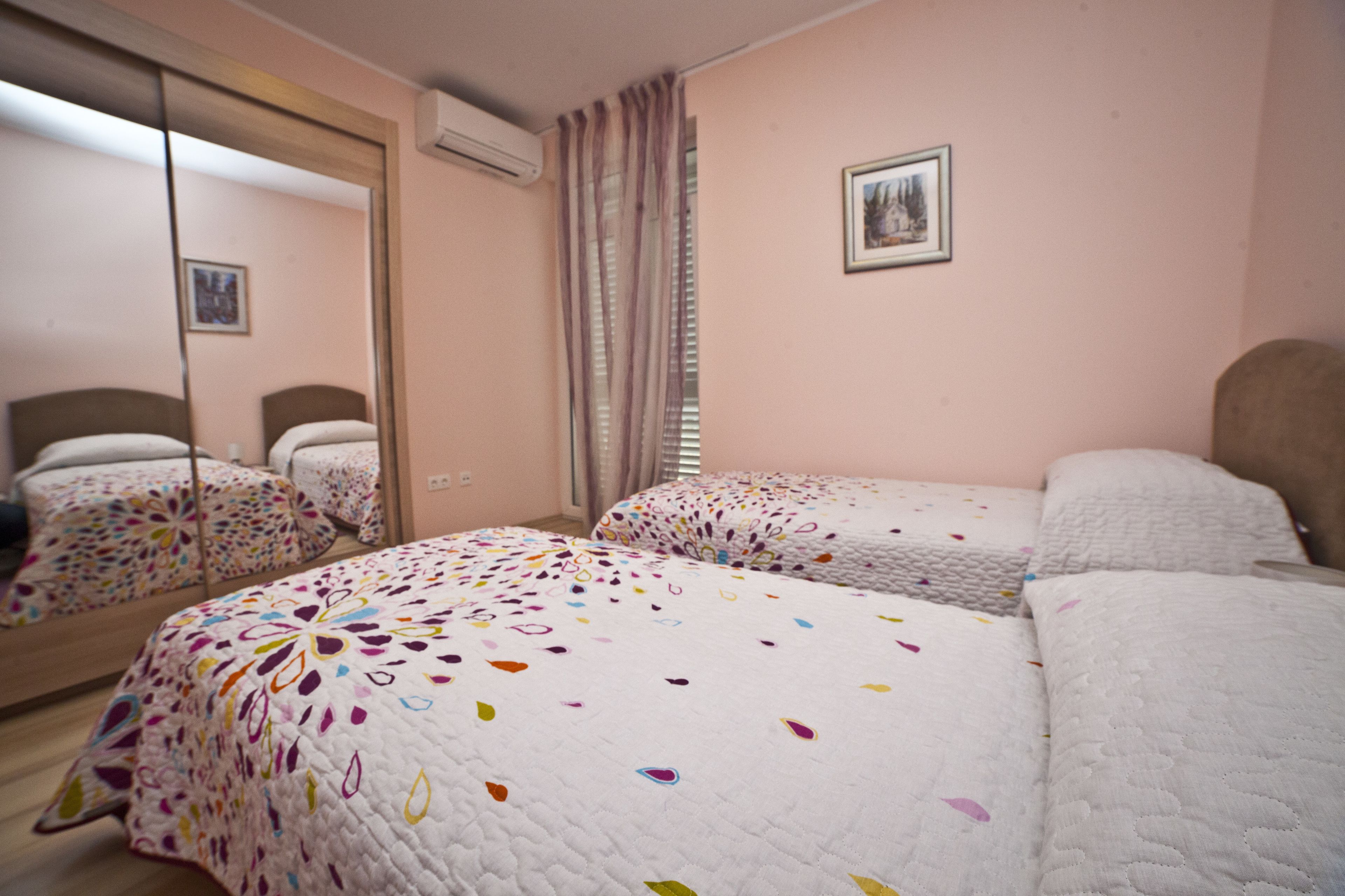 A hotel room with two beds, a large mirror, and a picture on the wall.