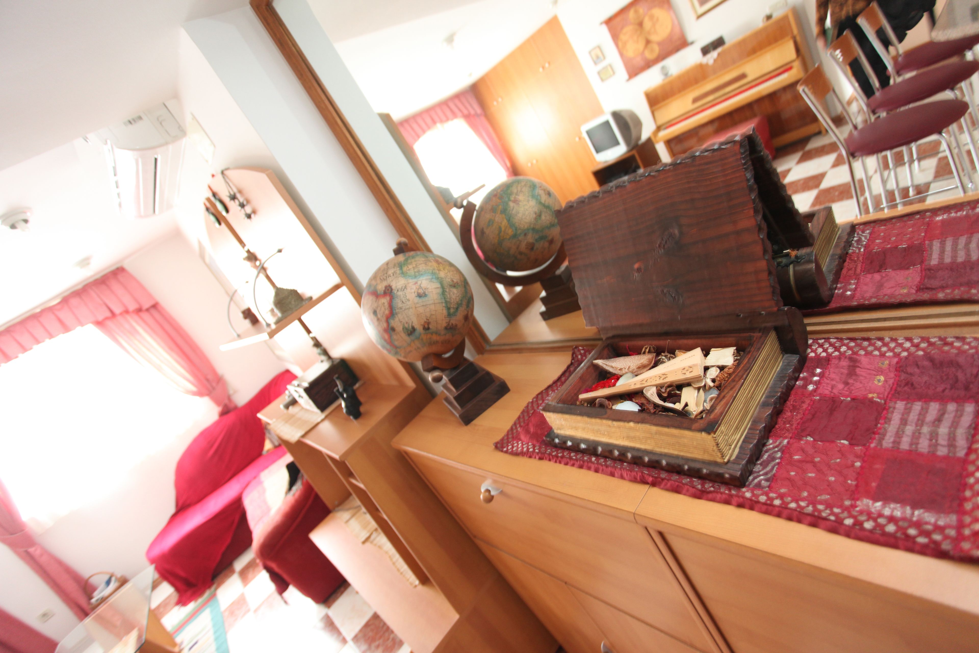 A room with a wooden desk, a globe, a book, and a red chair.